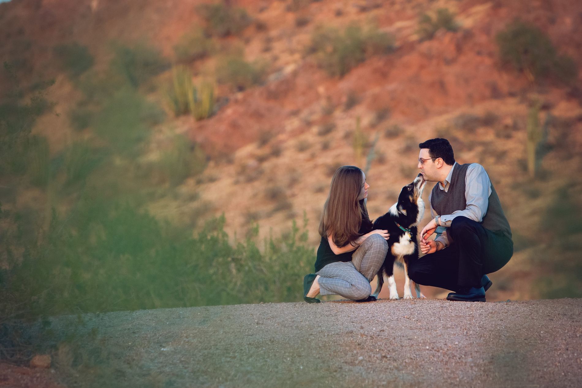 Dr. Berman and Dr. Kitchen with their dog on a wide Sonoran desert hillside at dusk